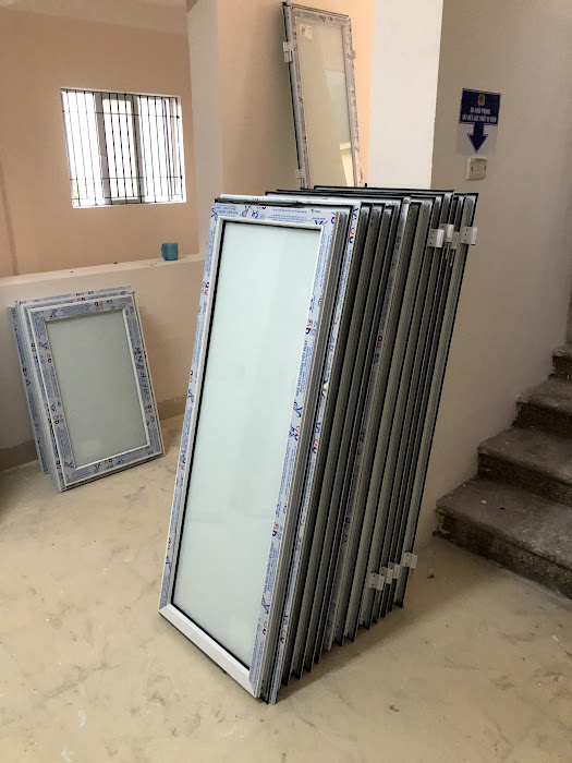 Các khung cửa kính nhôm kính trắng mới xếp chồng trong nhà chờ lắp đặt